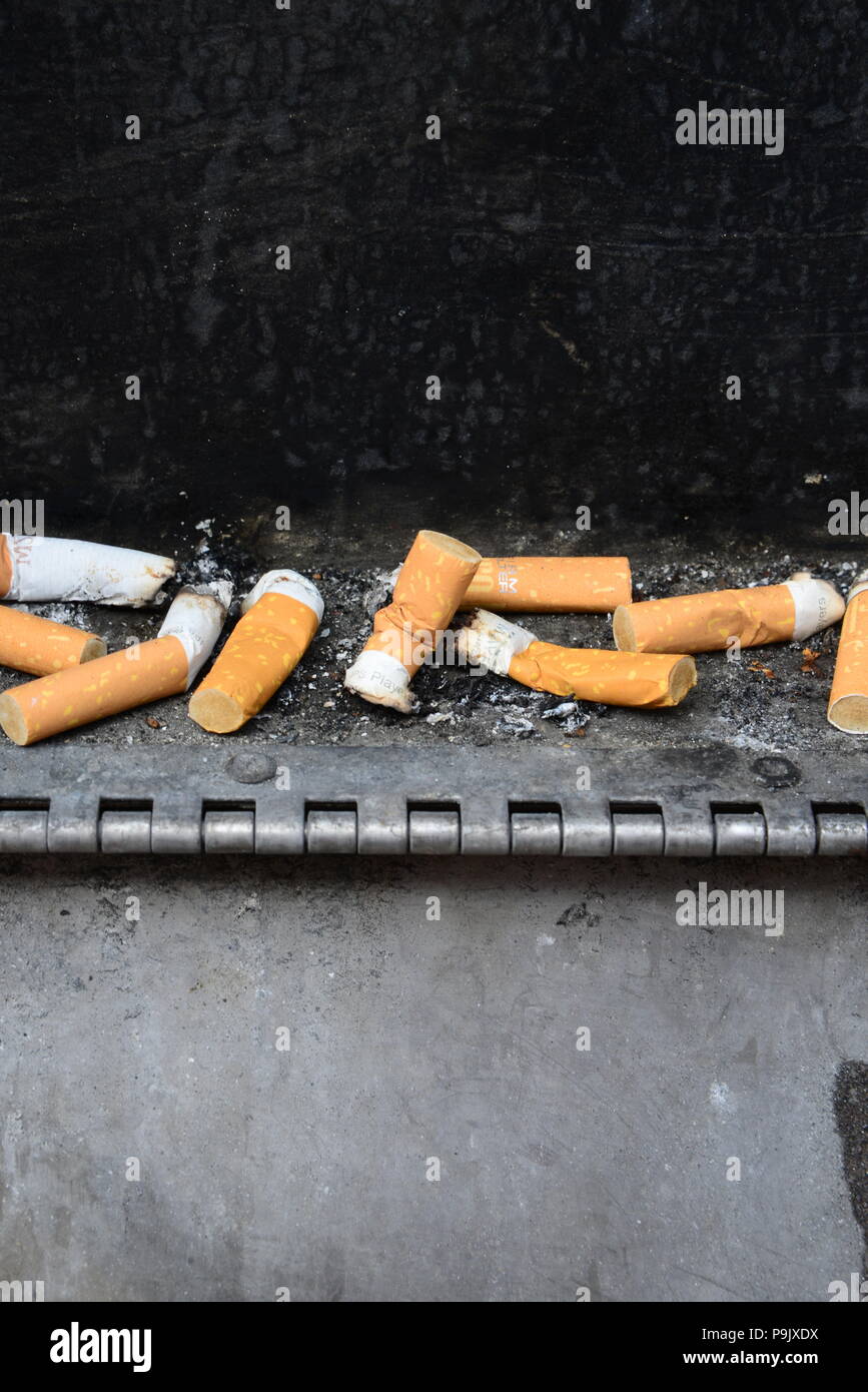 Cigarette stubs in public ashtray Stock Photo