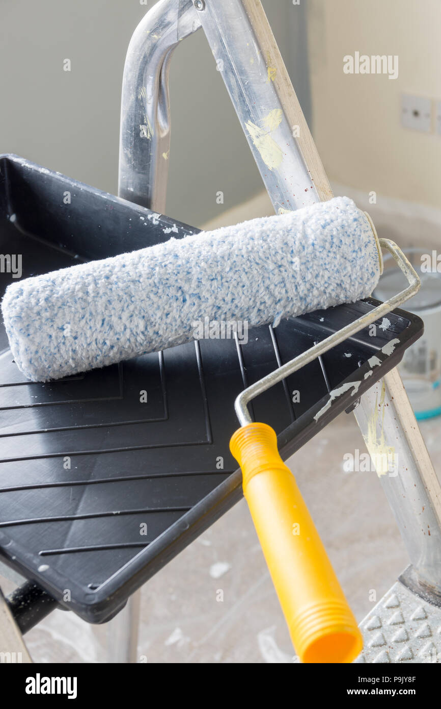 Painting and decorating with a roller and tray on a set of metal step