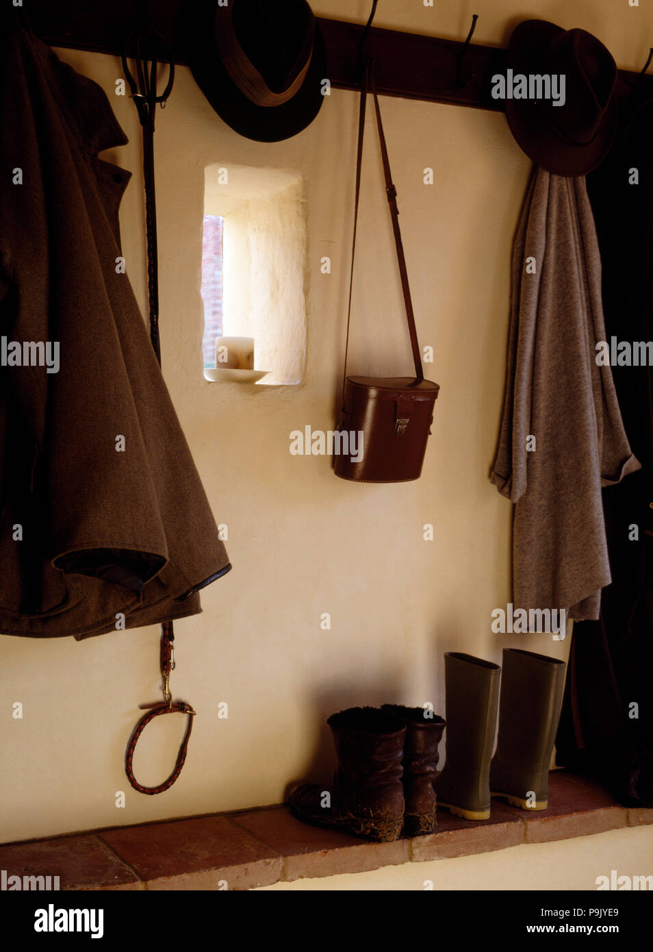 Coats and hats on hooks above boots in a cottage hall Stock Photo