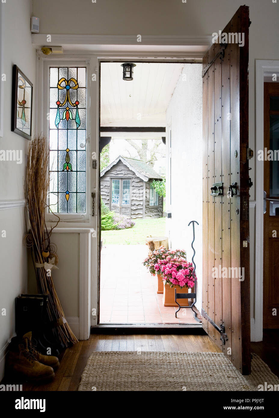 Stained glass window beside open oak front door in small hall Stock