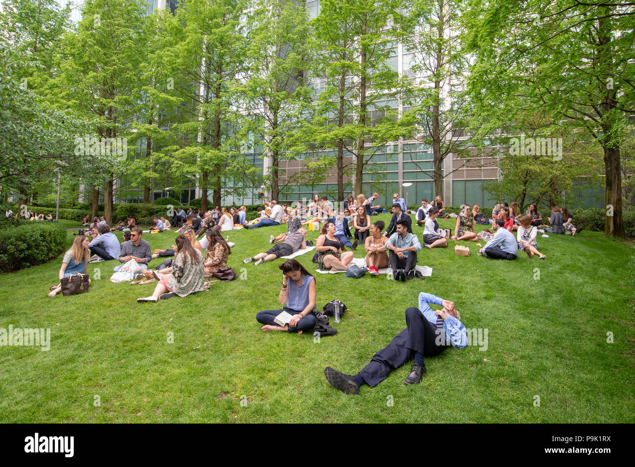 Office workers having their lunch break in Jubilee Park, Canary Wharf, London, UK Stock Photo