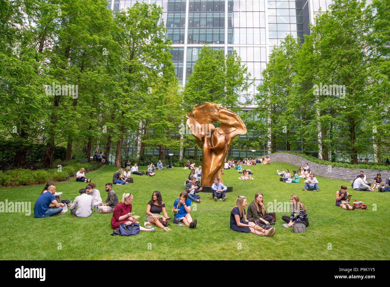 Office workers having their lunch break in Jubilee Park, Canary Wharf, London, UK Stock Photo
