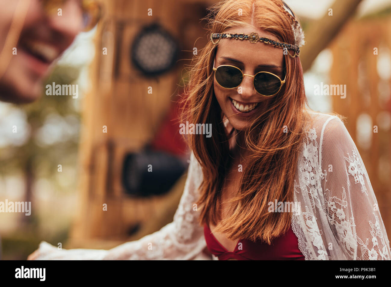 Happy young hippie woman dancing outdoors at music festival. Female hipster in sunglasses having fun at music festival. Stock Photo