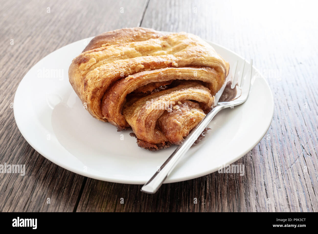 close-up shot of Franzbroetchen pastry on plate on rustic wooden table Stock Photo