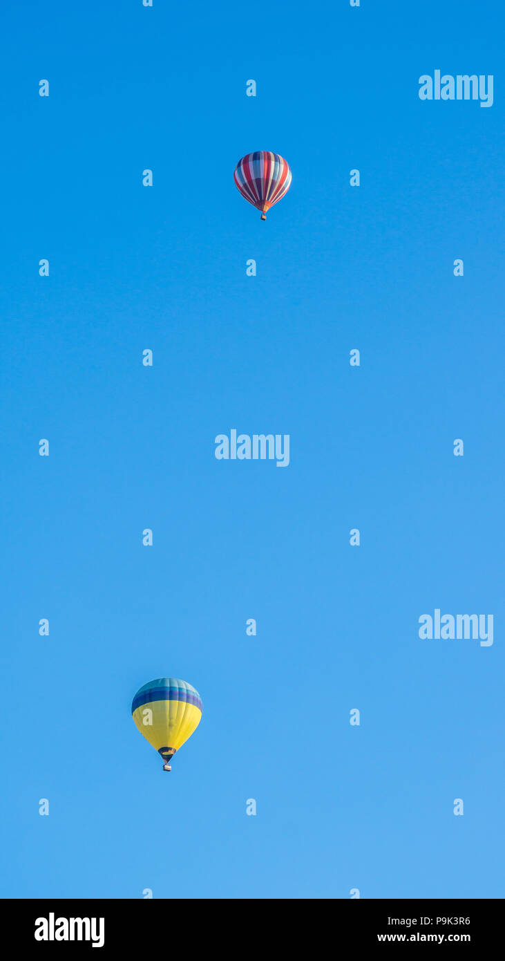 Two multi color hot air balloons flying into blue sky Stock Photo