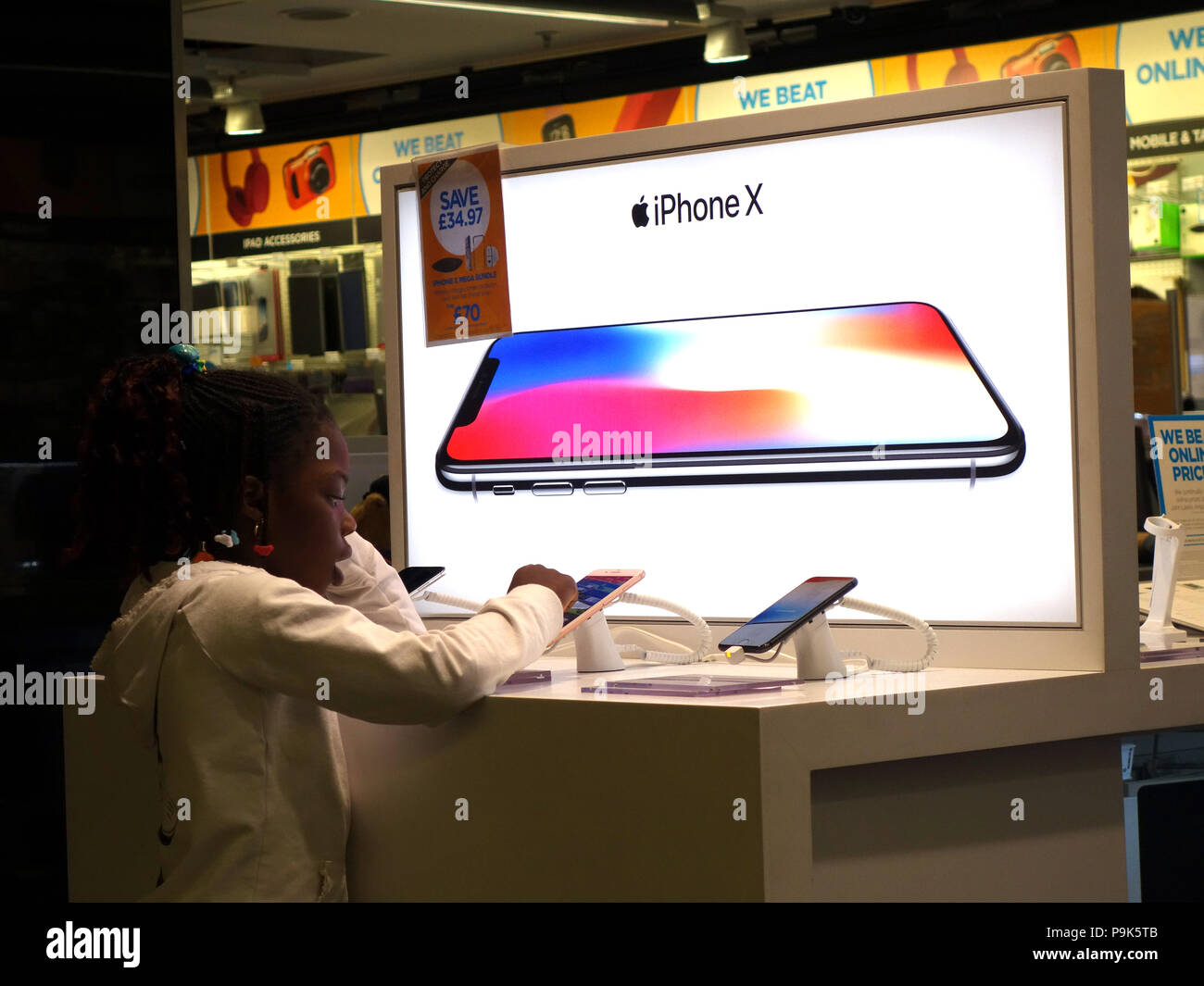 Young people looking at the electronic items on sale in the Duty Free Lounge Electronic section at Manchester Airport. IPhone X Advert Stock Photo