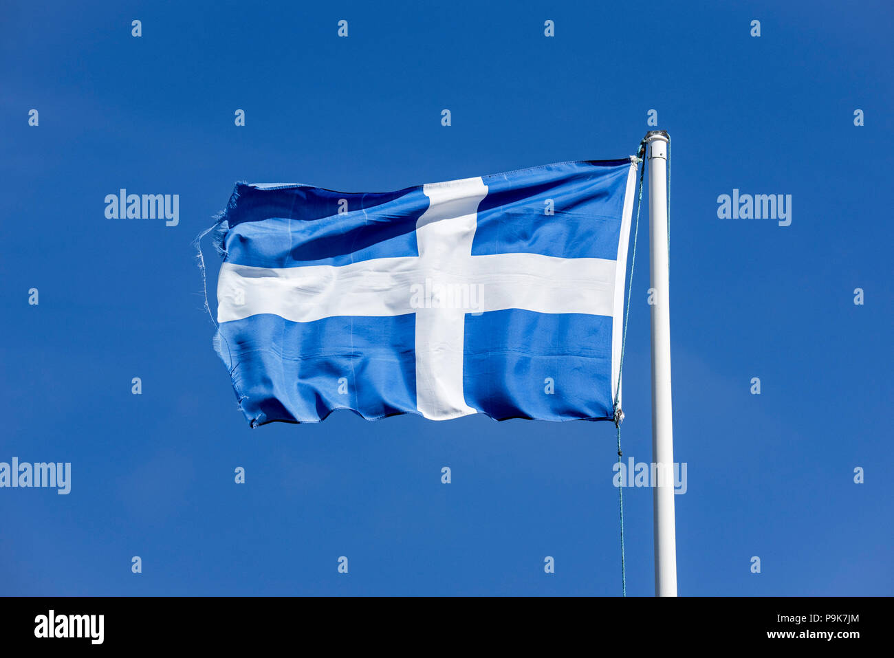 Worn flag of Shetland, white Nordic cross on a blue background, blowing in the wind against blue sky, Shetland Islands, Scotland, UK Stock Photo