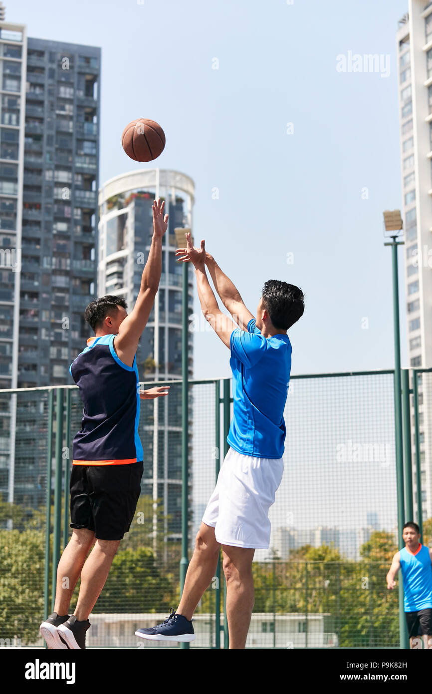 young asian adult players playing basketball on outdoor court. Stock Photo