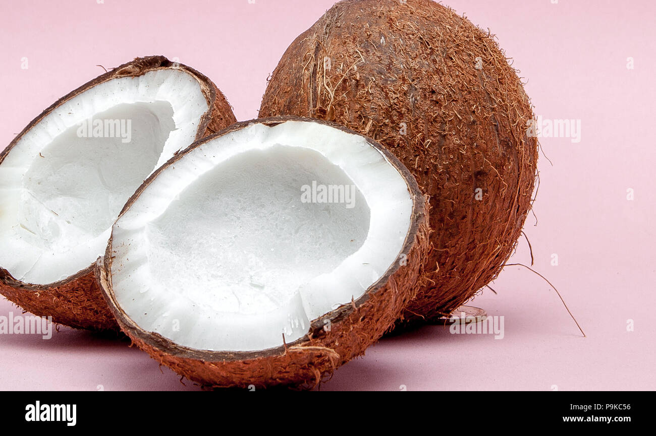 Coconut on a pink background. Minimal style. Two halves of coconut
