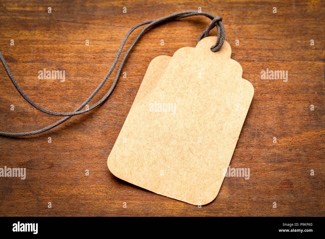 blank paper price tag with a long twine against grained rustic wood ...