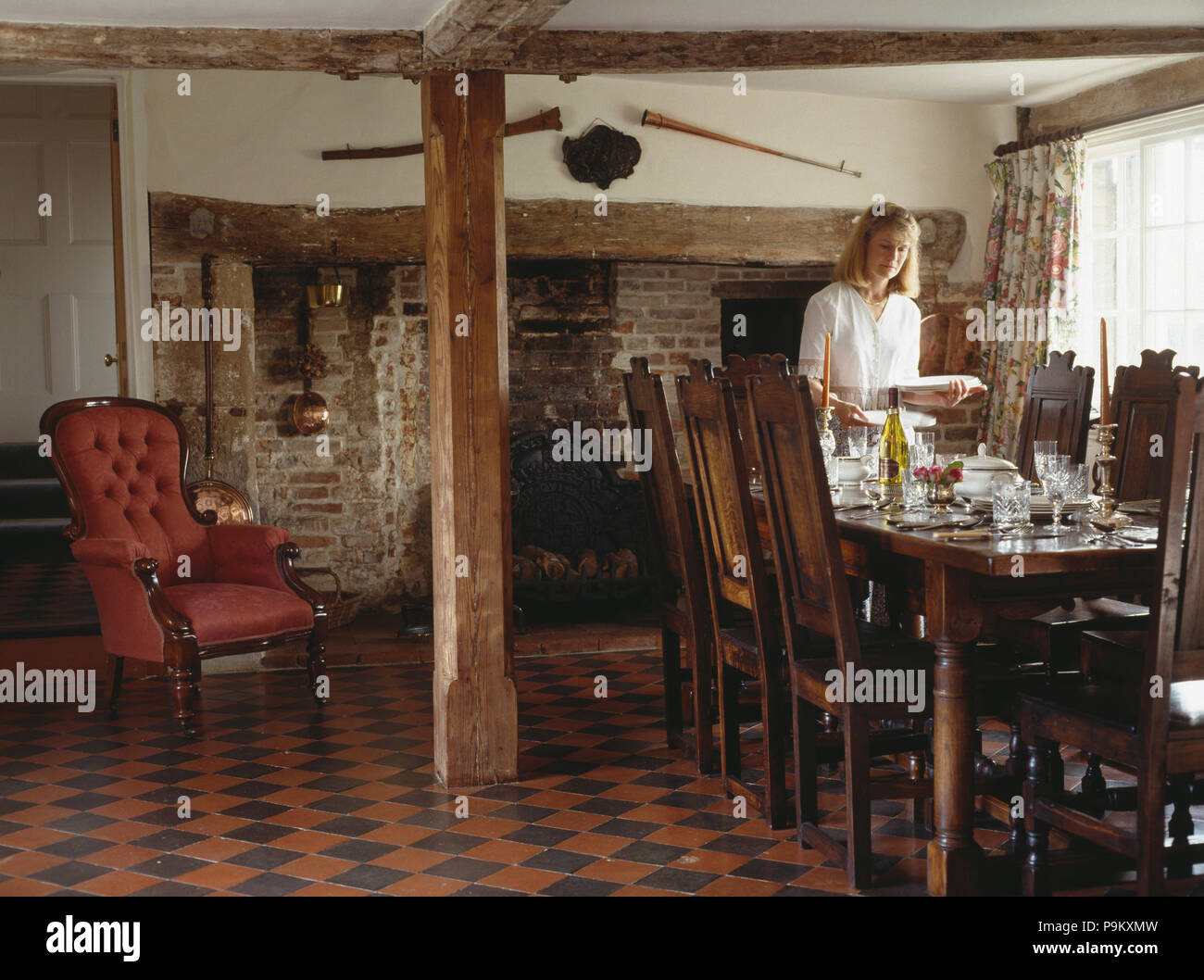Woman setting the table in country dining room with original encaustic ...
