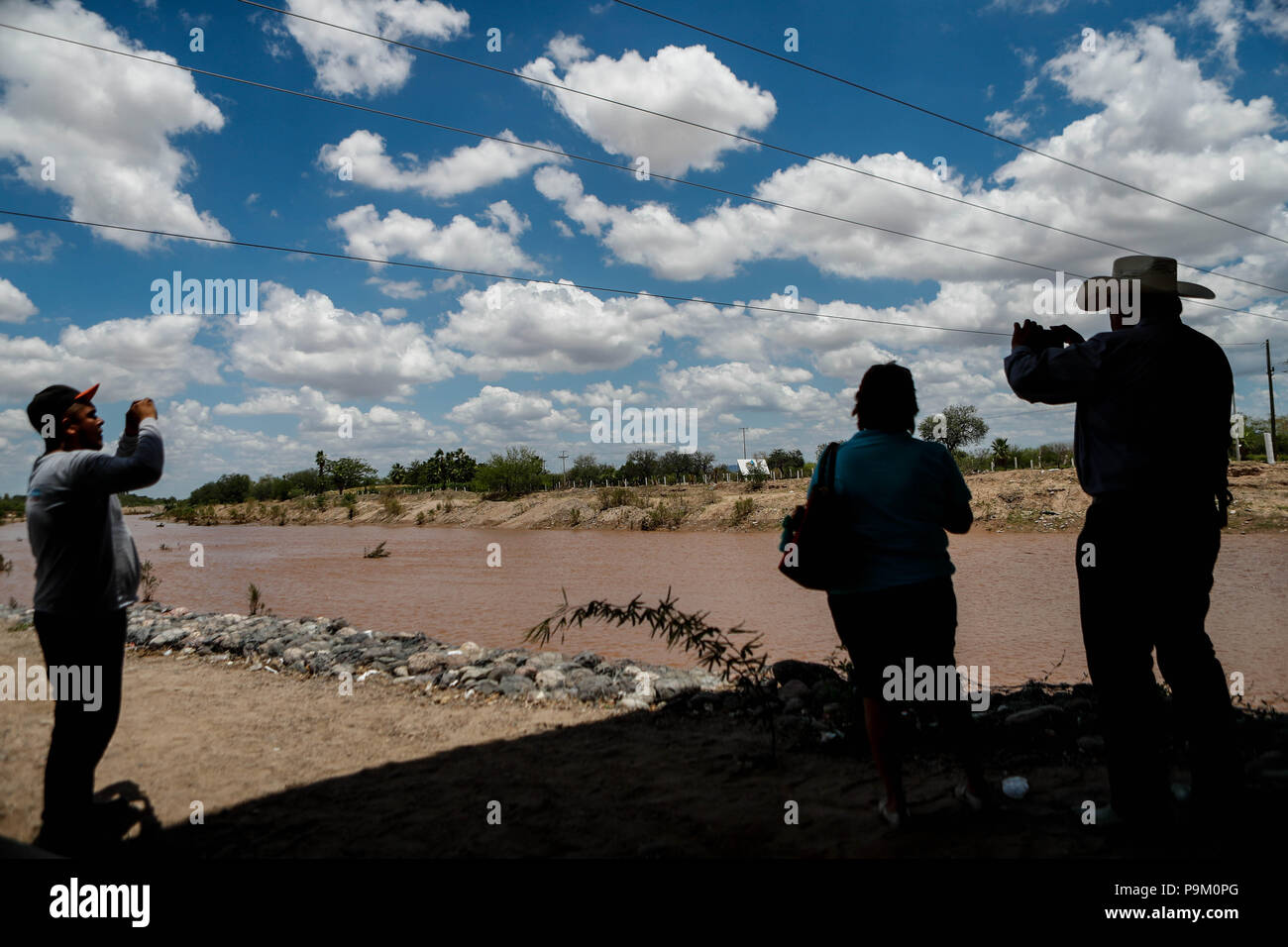 El Saucito, Mexico. 18th July, 2018. Hermosillonses observe the water channel of this morning in the San Miguel River. Rainwater flow in the San Miguel River as it passes through San Pedro El Saucito. Stream of water that flows into the Abelardo L. Rodr'guez dam. The water current has been generated from the precipitation that has occurred in the Sierra de Sonora. Credit: NortePhoto.com/Alamy Live News Stock Photo