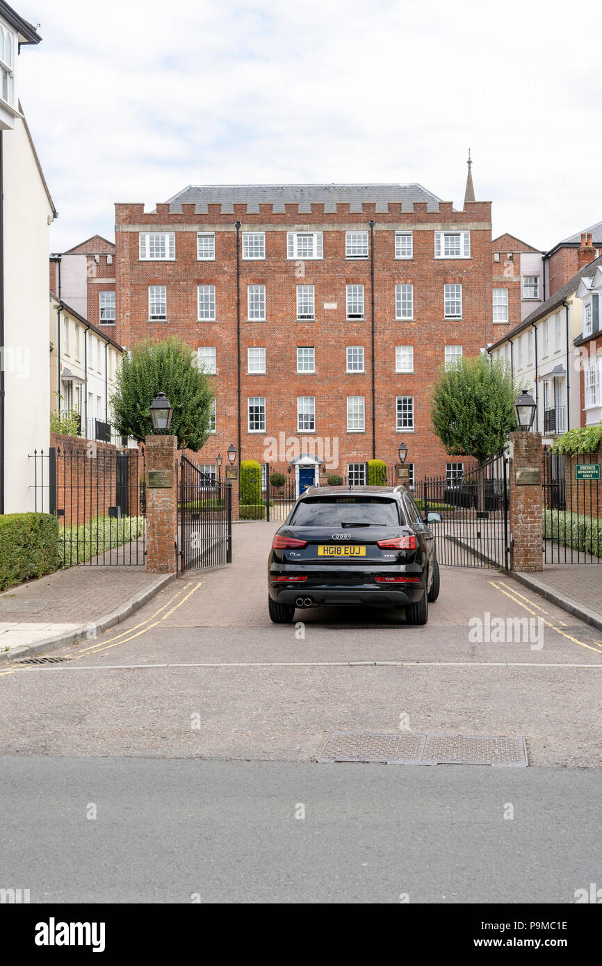 Car entering gates in front of tall brick building Stock Photo