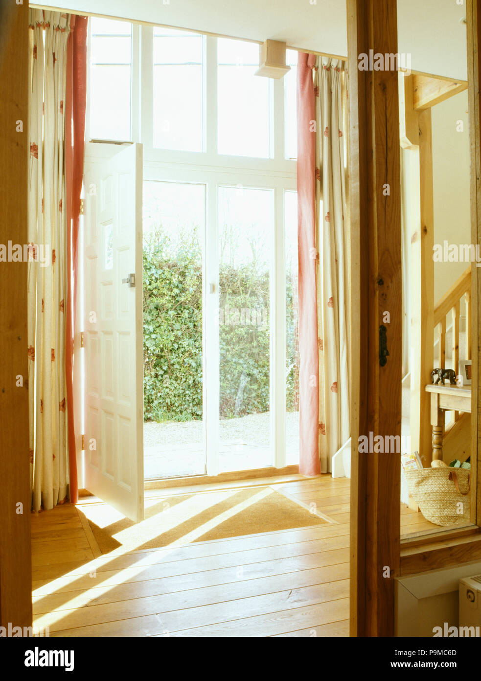 Open glass doors in barn conversion hall with wooden flooring Stock Photo