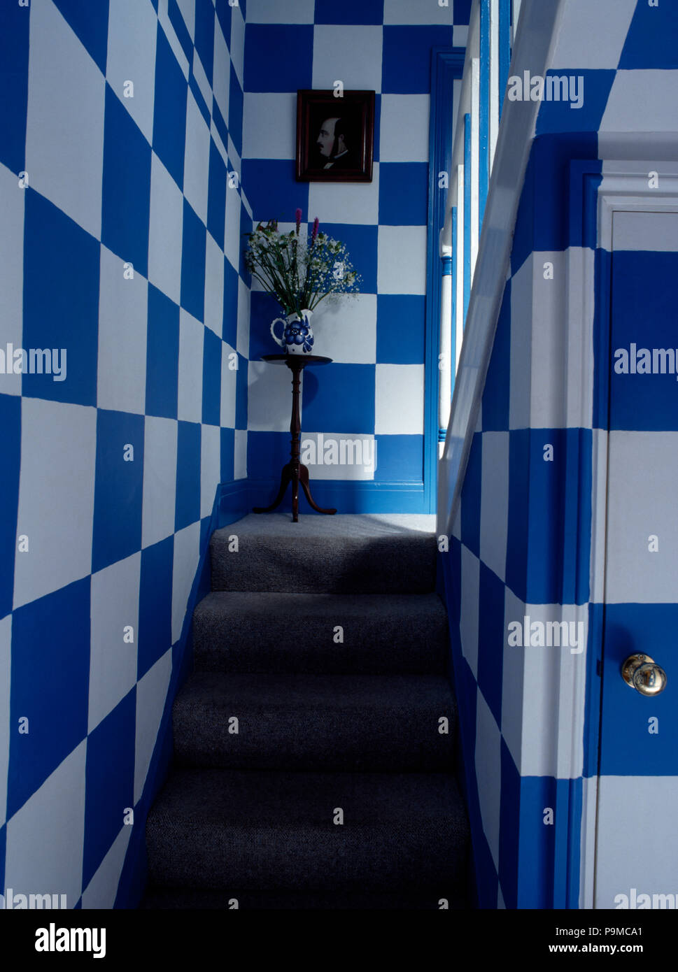 Grey carpet on stairs with walls painted in large blue+white checks Stock Photo