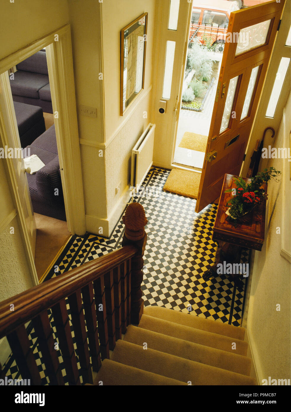 Birdseye view of black+white encaustic tiles in townhouse hall with glazed panels in open front door Stock Photo
