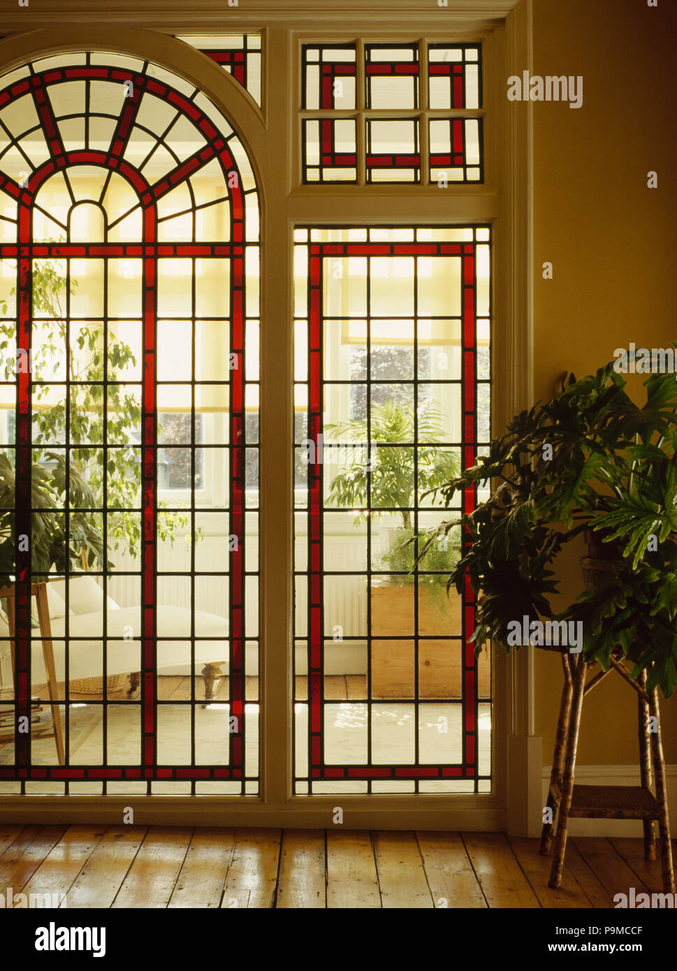 Arched glass door and windows with red stained glass panels in traditional hall Stock Photo