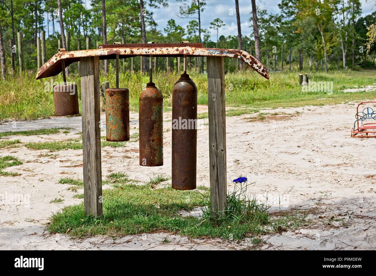 Huge homemade wind chimes made from cylinders hang outside in a wooded area Stock Photo