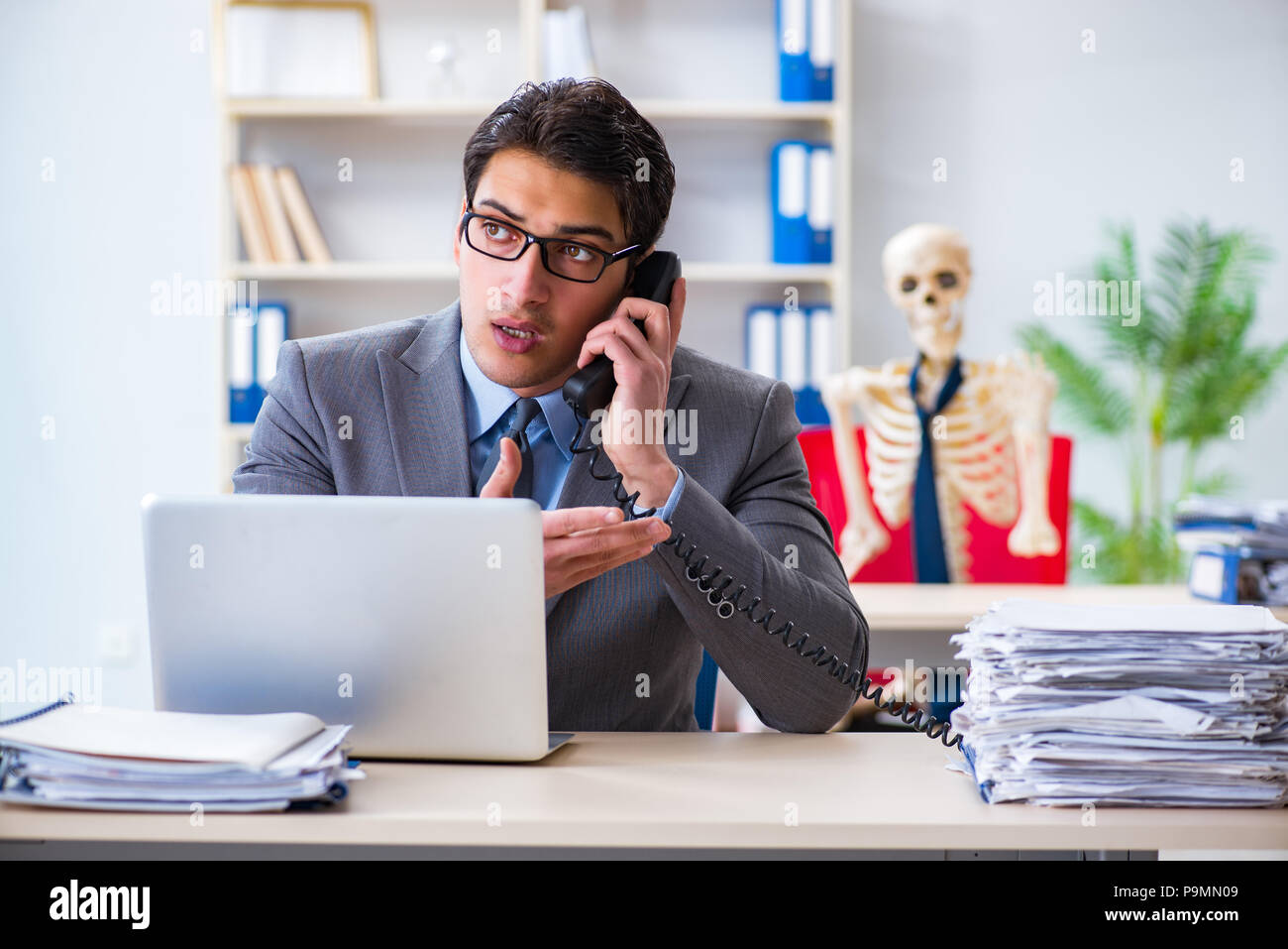 Businessman working with skeleton in office Stock Photo