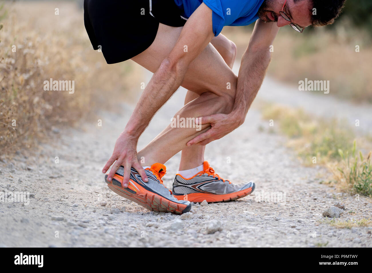 close up of runner touching painful twisted or broken ankle shin or calf athlete runner training accident sport running ankle sprain concept Stock Photo