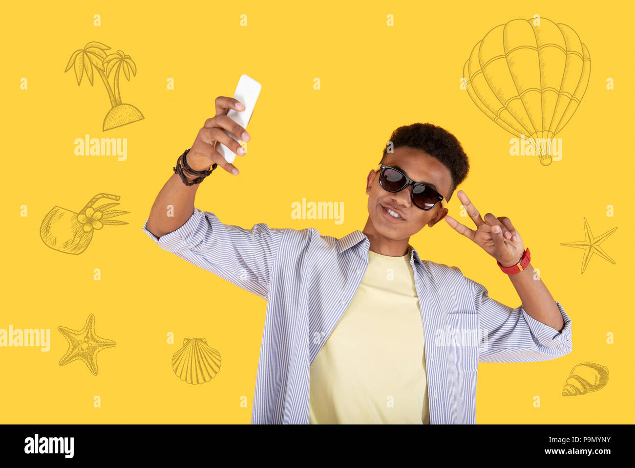 Cheerful student putting his hand up while taking a selfie Stock Photo