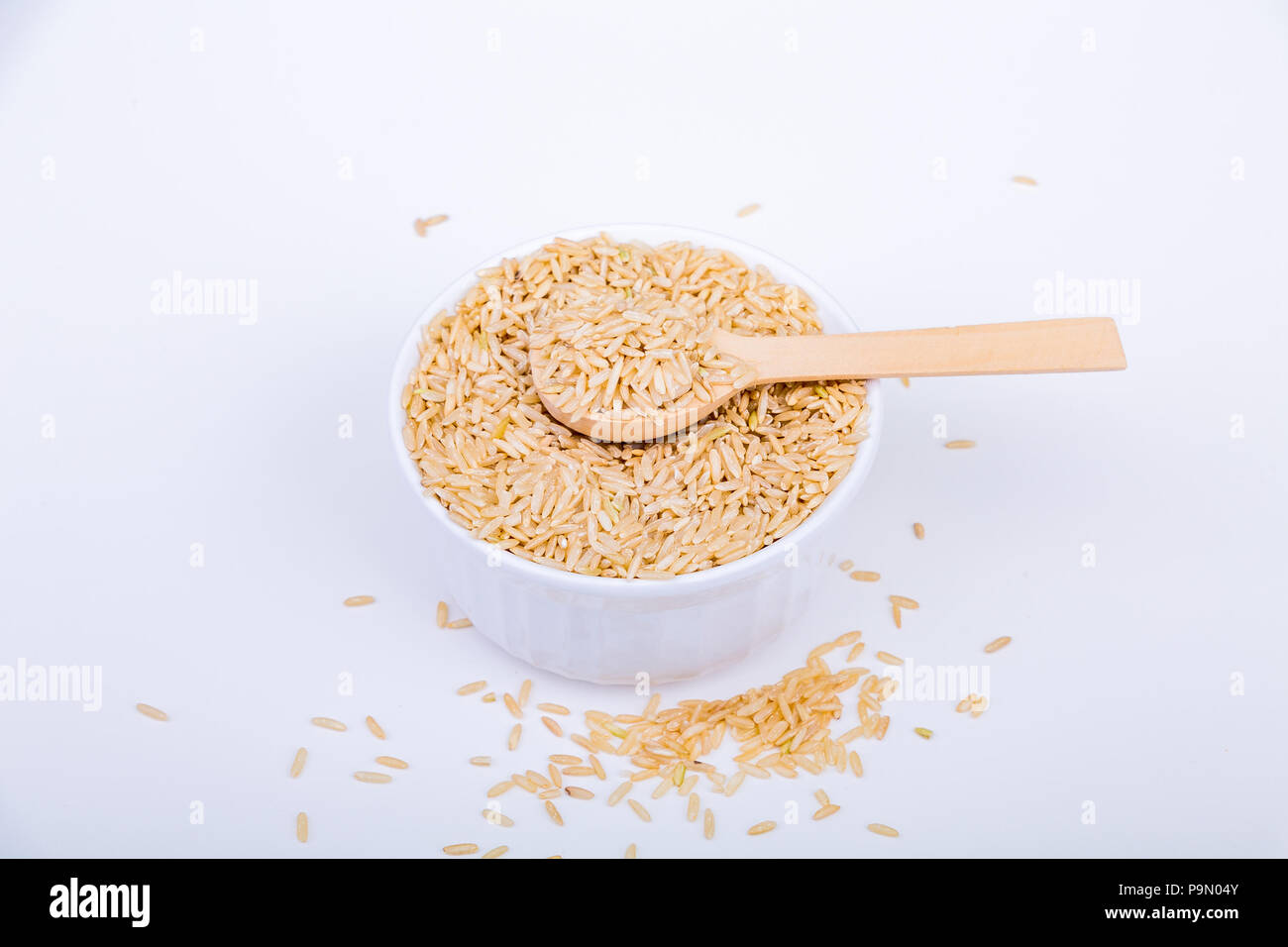 Brown Rice in a White Bowl with Wood Spoon Stock Photo