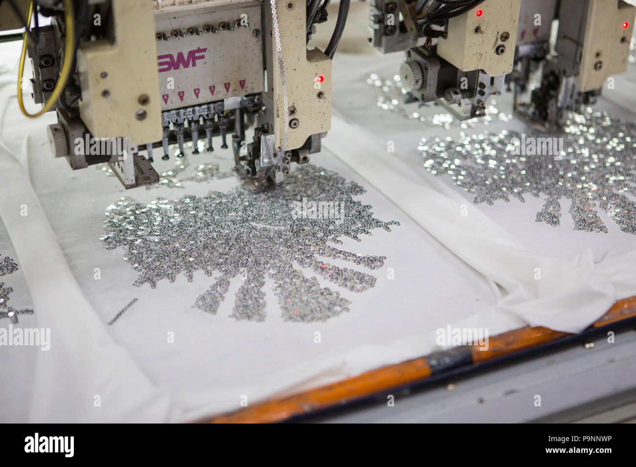 Sewing machines, print a sequin design on a bio cotton T-shirt at a factory, where organic cotton is being used to make clothes, Indore, India Stock Photo
