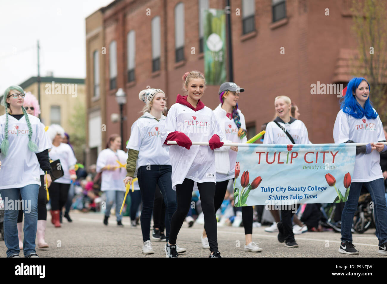 Holland, Michigan, USA - May 12, 2018 Members of Tulip City Beauty College smile and walk down the street while wearing colorful wigs at the Muziek Pa Stock Photo