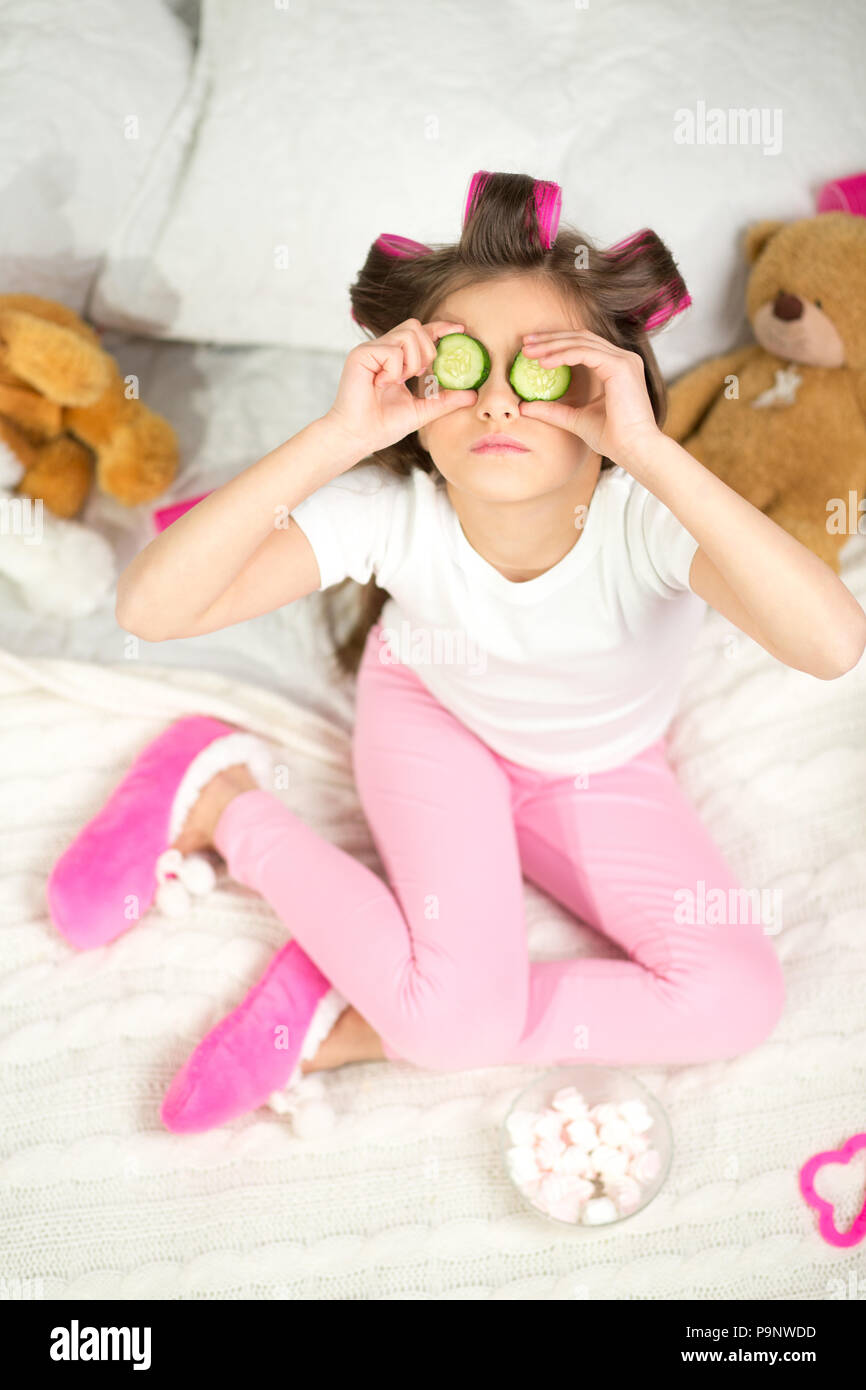 Little girl with cucumber slices on her eyes. Stock Photo