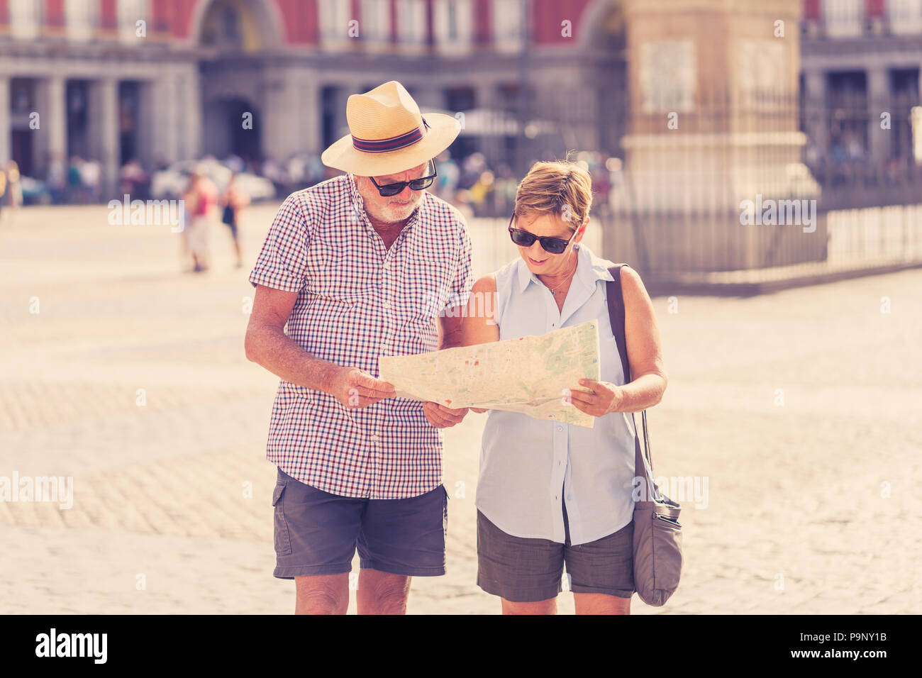 Happy active retired tourist couple searching for their location in Plaza Mayor Madrid in travel around Europe holidays retirement concept. Stock Photo