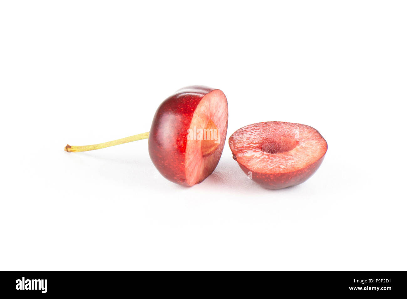 Group of two halves of sweet bright red cherry one cut in halves isolated on white Stock Photo
