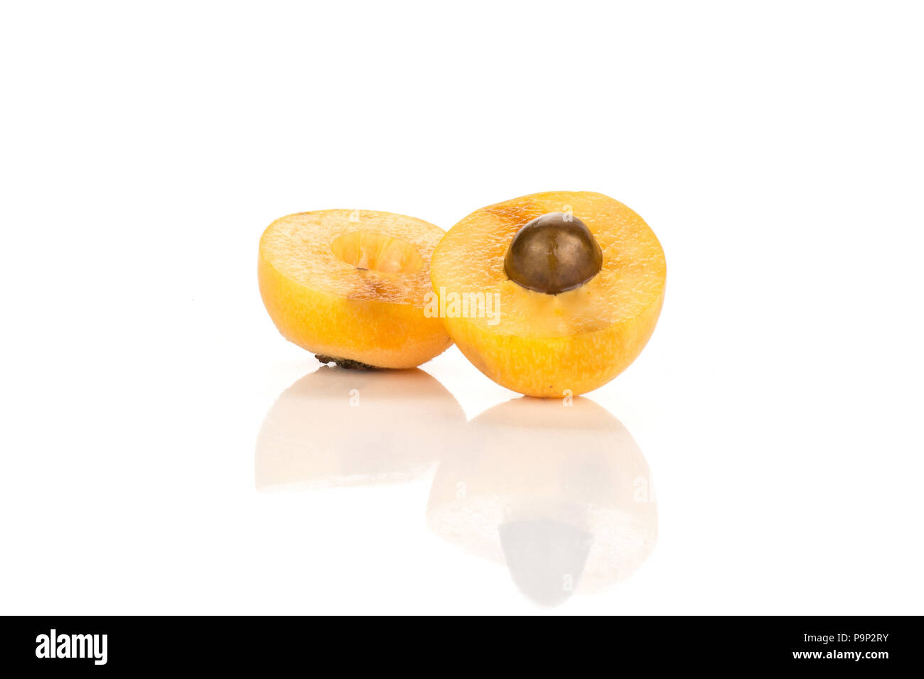 Two sliced fresh orange Japanese loquat halves isolated on white