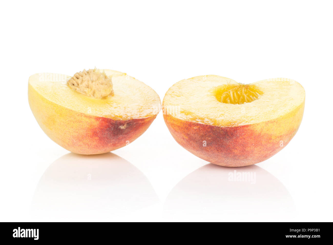 Two halves of yellow peach isolated on white background cross section with a drupe inside Stock Photo