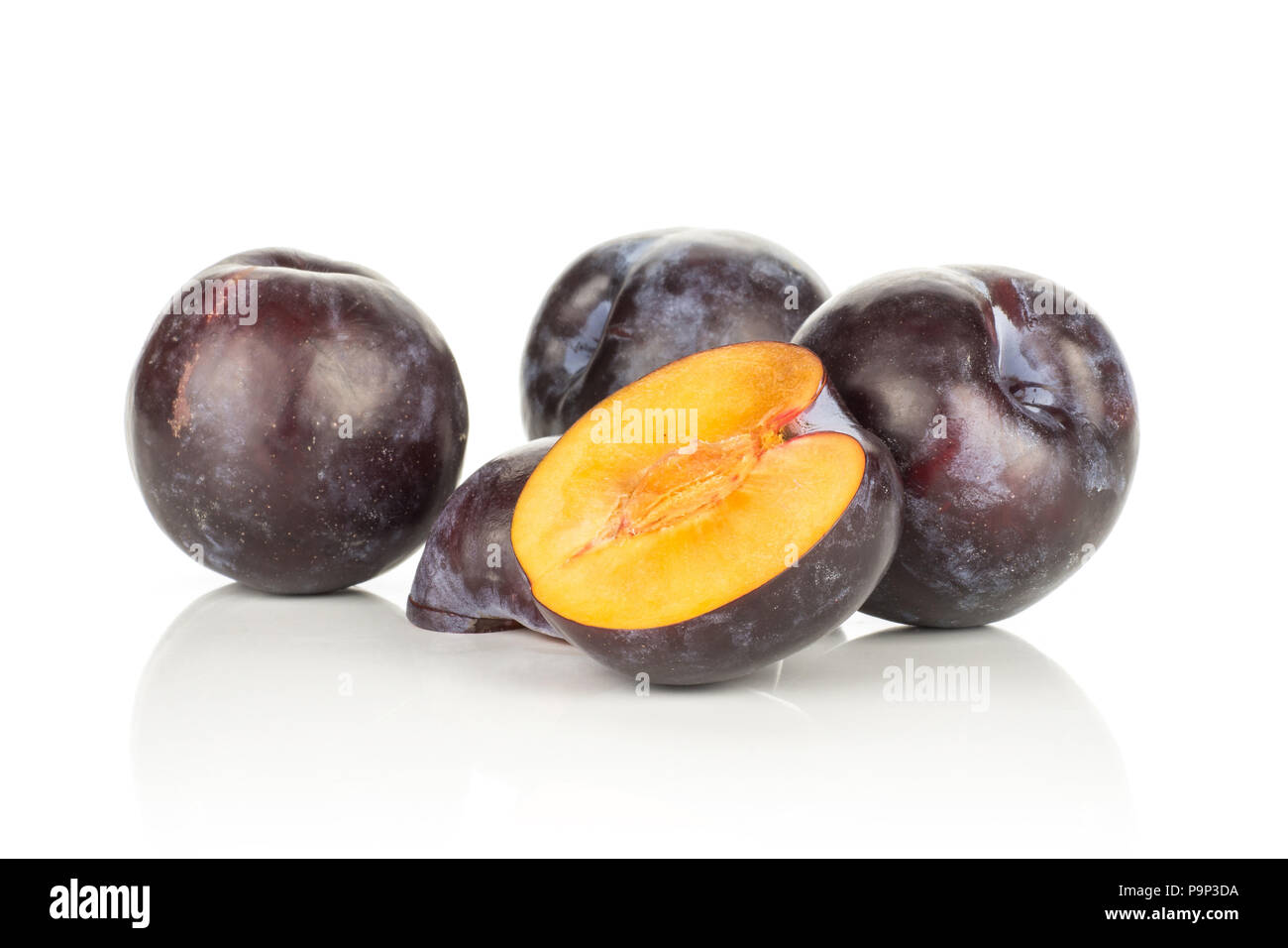 Three red blue plums and two halves isolated on white background Stock Photo