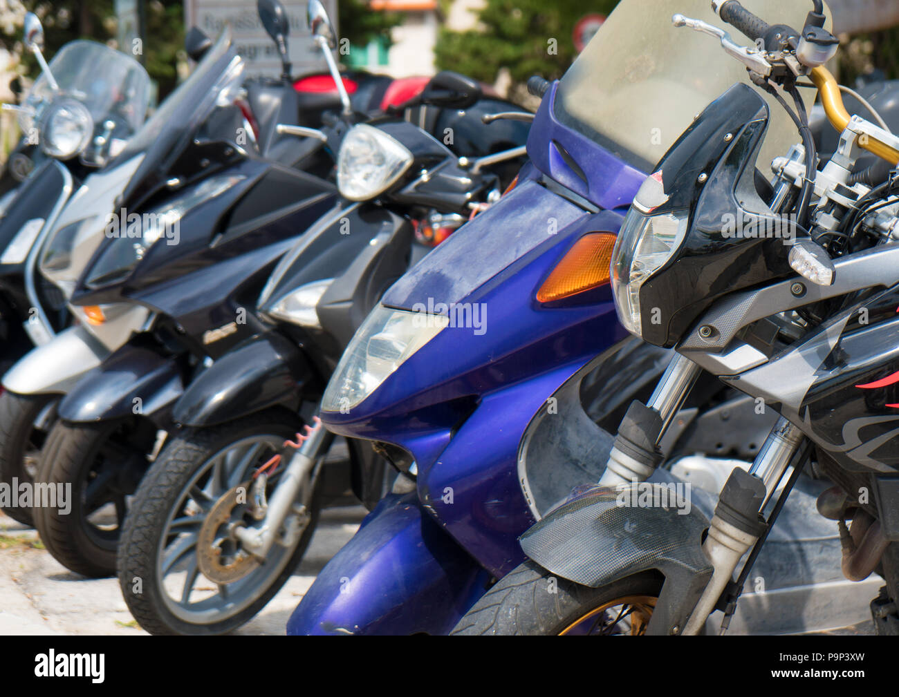 Many mopeds and scooter motorcycles parked on the street. Stock Photo