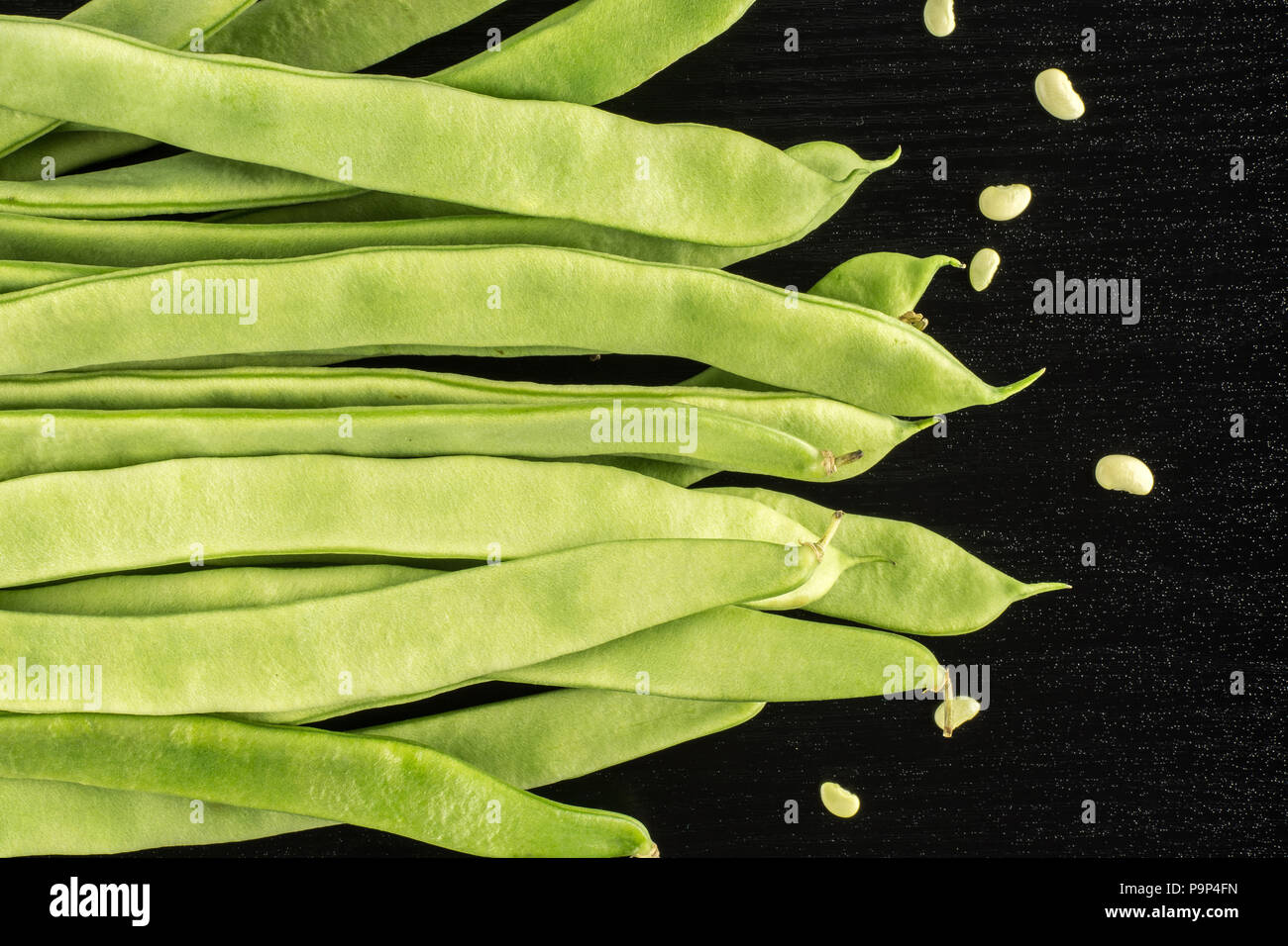 Flat green beans with seeds top view isolated on black wood background