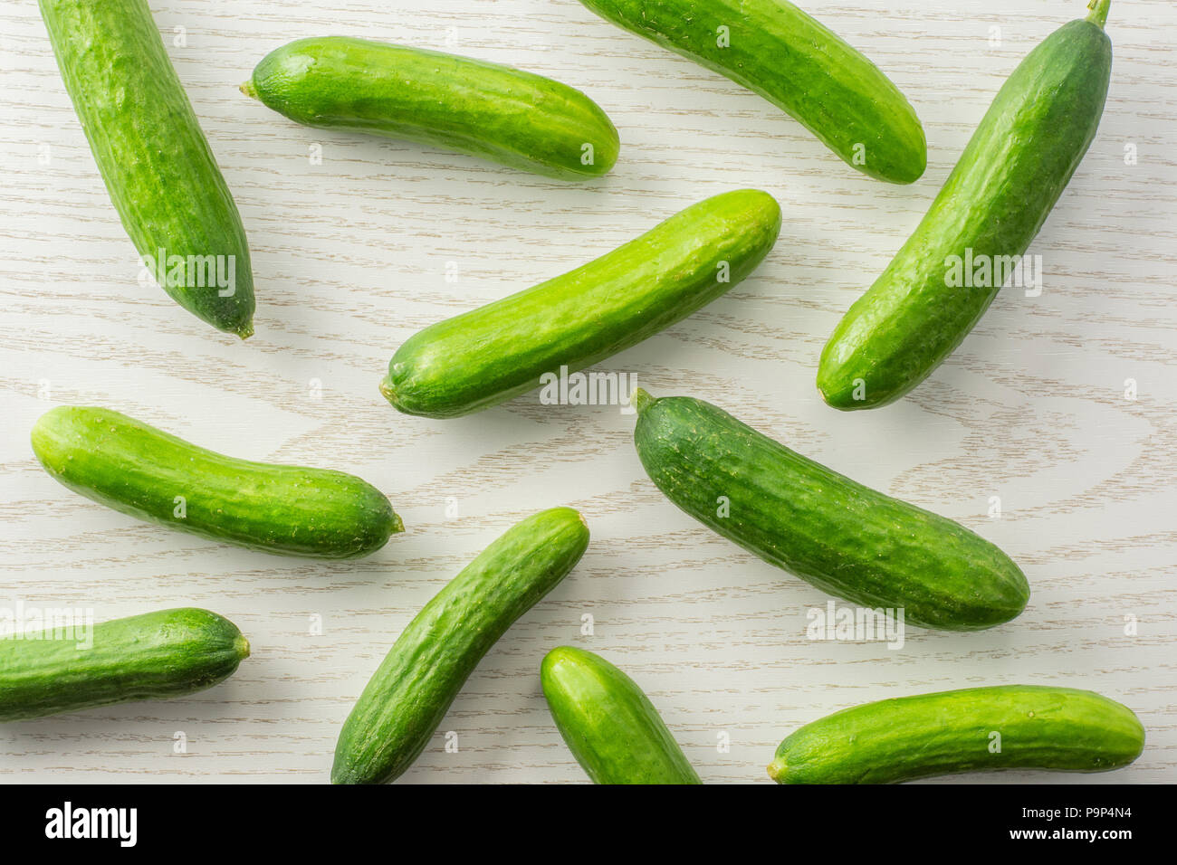 https://c8.alamy.com/comp/P9P4N4/fresh-mini-cucumbers-flatlay-on-grey-wood-background-P9P4N4.jpg