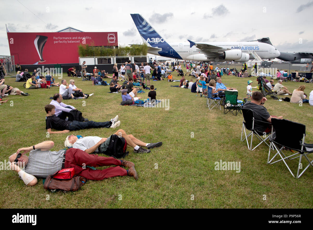 Visitors relax on the grass near Airbus A380 widebody jet airplane during a public day at the Farnborough International Airshow, UK Stock Photo