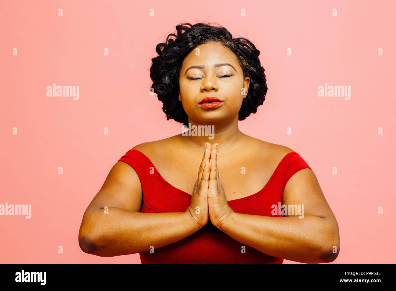 Inner peace/ Young woman in red, isolated on pink background Stock Photo