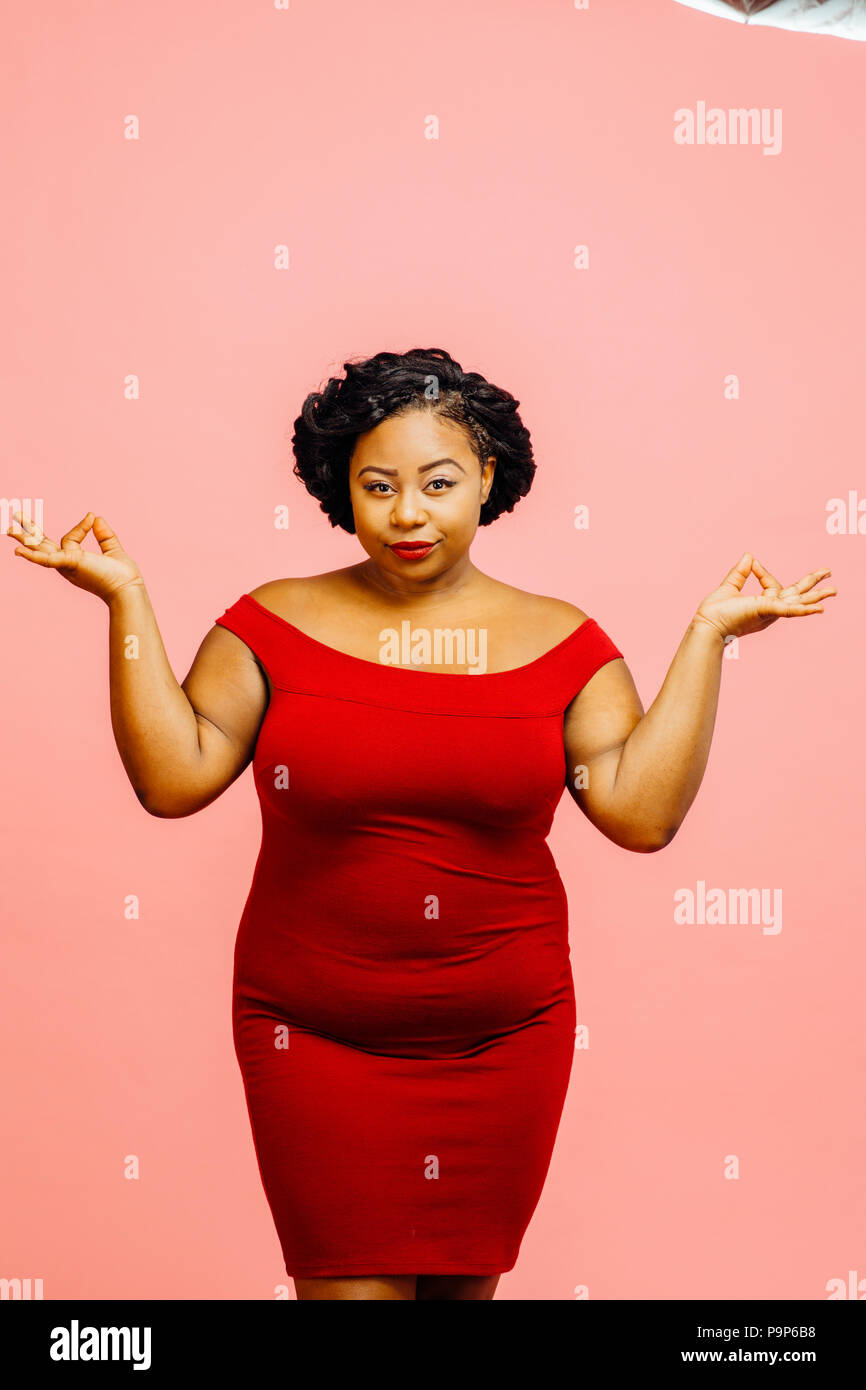 Inner peace/ Young woman in red with hands on her sides, isolated on pink background Stock Photo