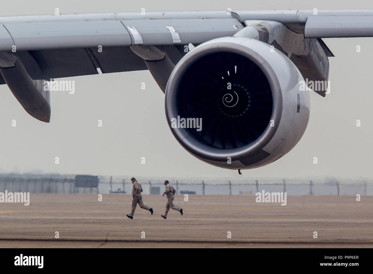 Two men run behind the Rolls-Royce Trent 900 engine at the Airshow China 2014 in Zhuhai, China Stock Photo