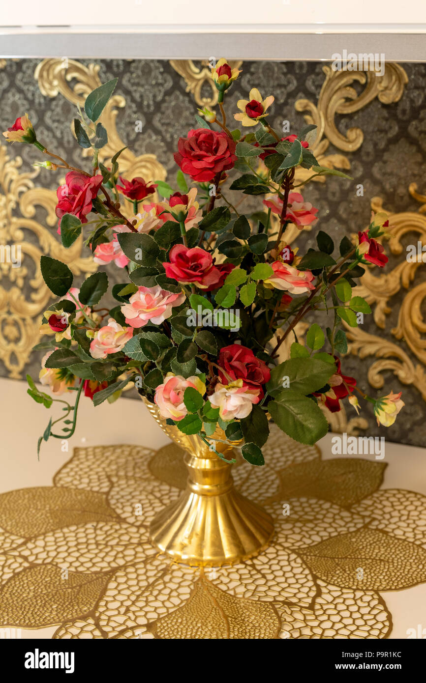 Artificial flowers on an expensive chest of drawers Stock Photo