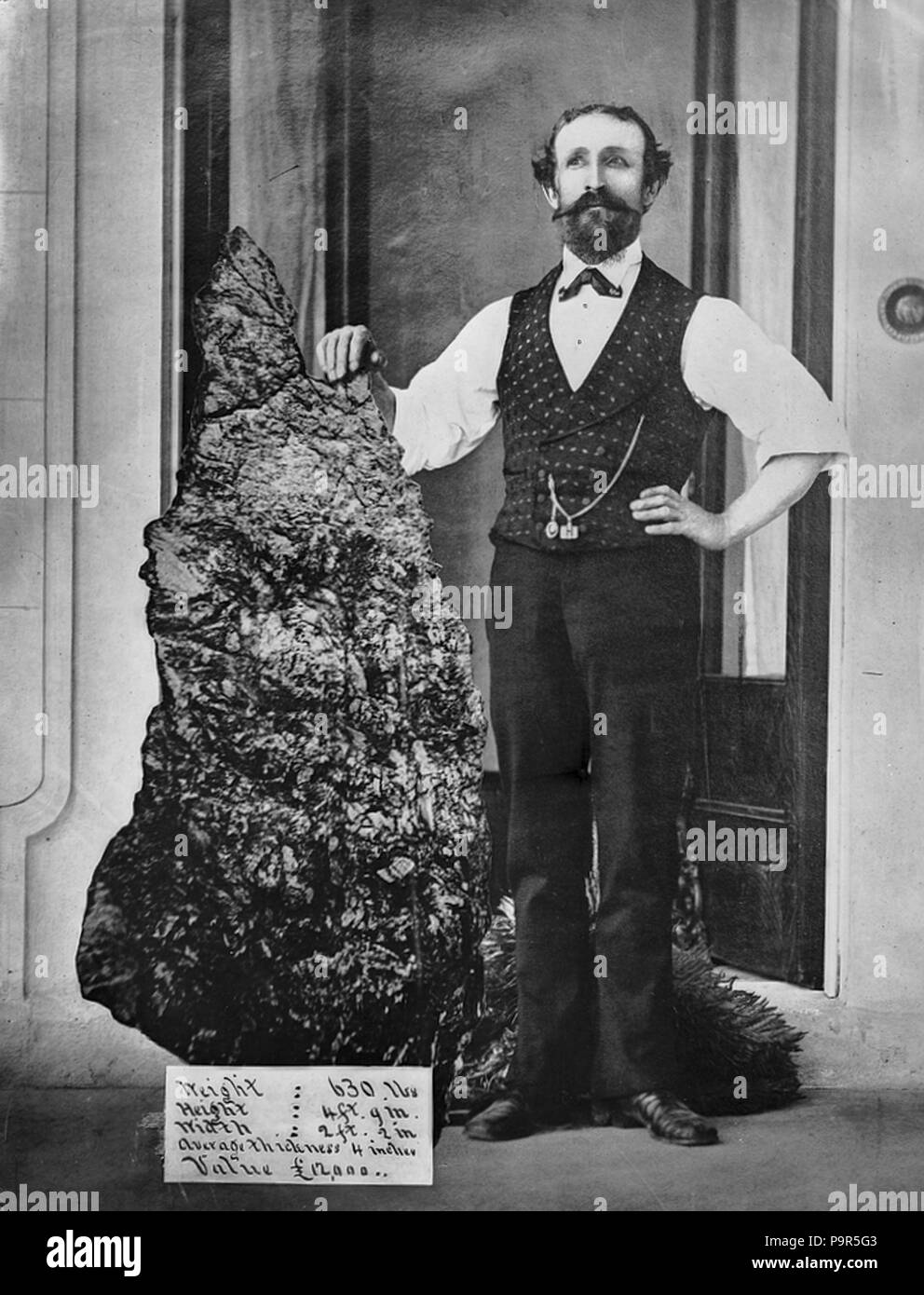 . English: Caption: 'Bernard Otto Holtermann and the world's largest 'nugget' of gold, North Sydney, ca. 1874-1876 / montage photograph by American and Australasian Photographic Company' The 'nugget' was found in Hill End, New South Wales by German prospector, Bernhard Otto Holtermannon 19th October 1872. More than half of the 630 lbs weight was pure gold, at that time having the value of 12,000 pounds ($24,000). Today, with gold worth say $1400 per ounce, the value today would be over $10 million. Three photographs were used to create this image of Holtermann, (supposedly holding the worlds'  Stock Photo