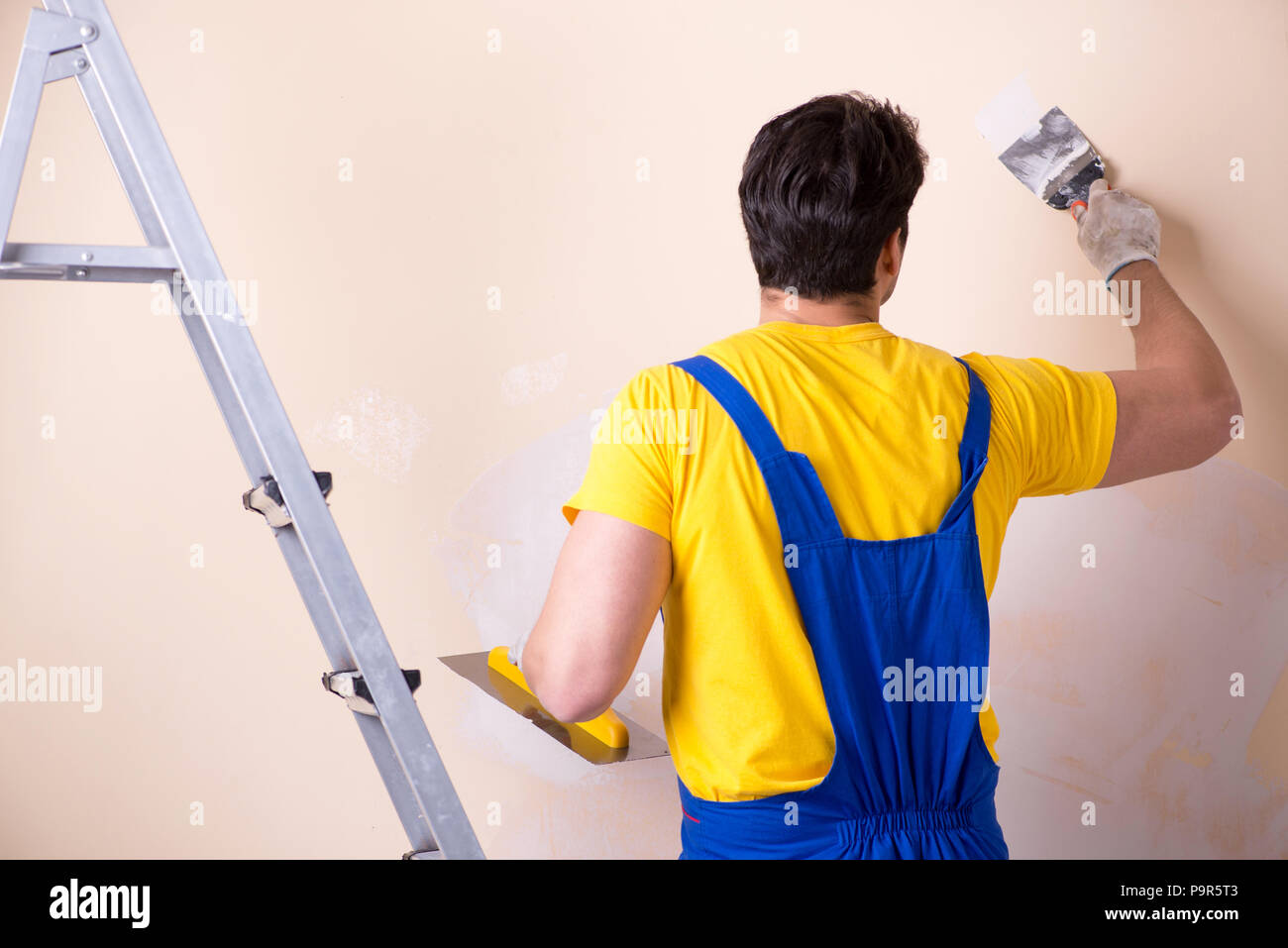 Young contractor employee applying plaster on wall Stock Photo