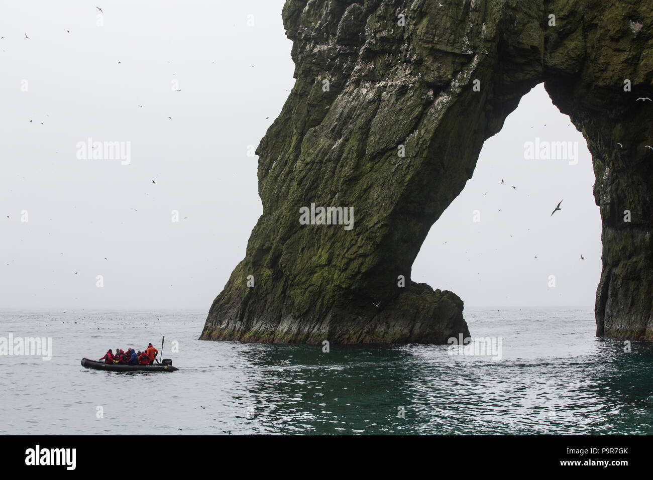 Zodiac with tourists exploring the bird cliffs of Bjørnøya (Bear Island), Svalbard Stock Photo