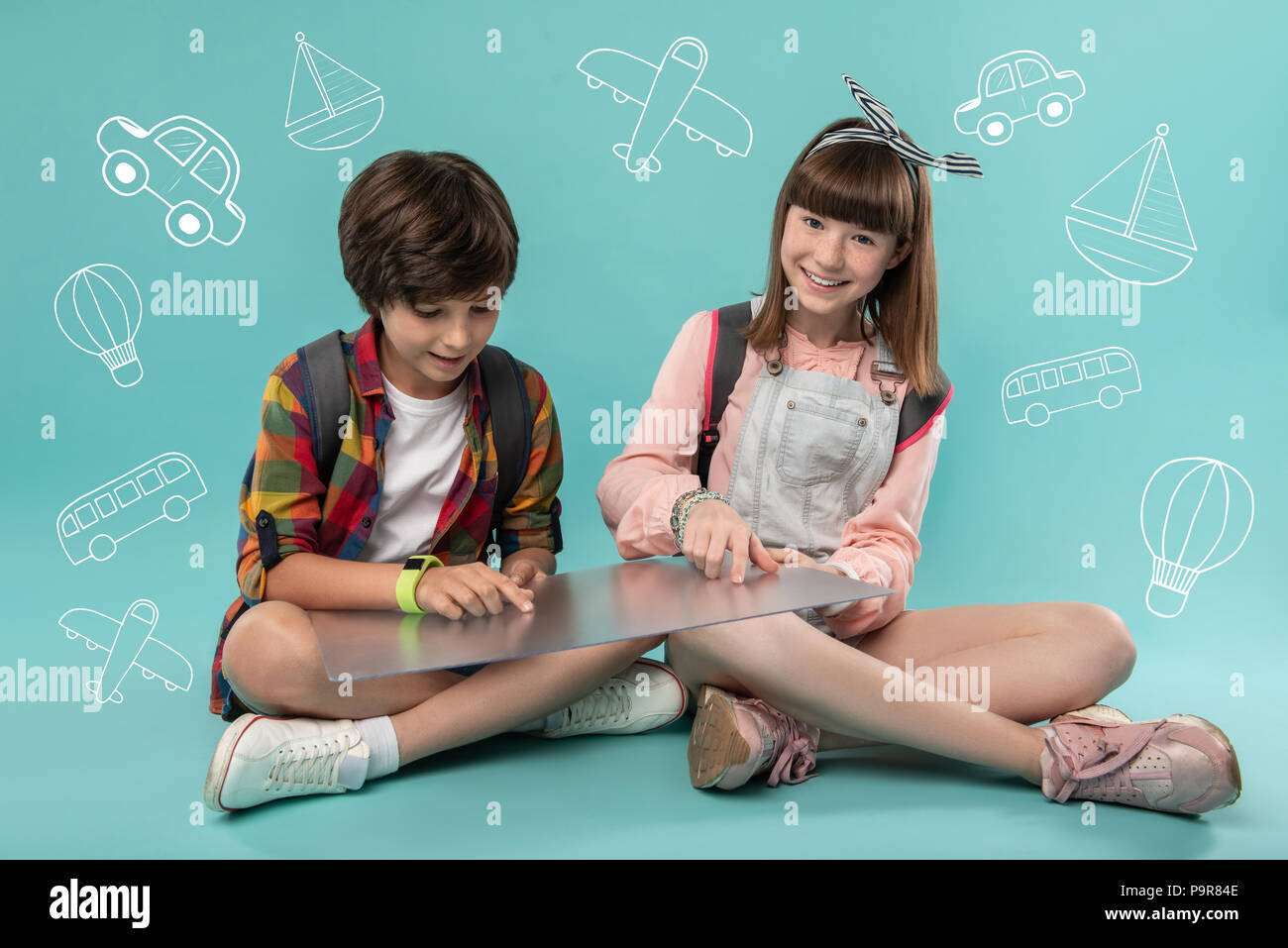 Happy kids sitting on the floor and using a transparent device Stock Photo