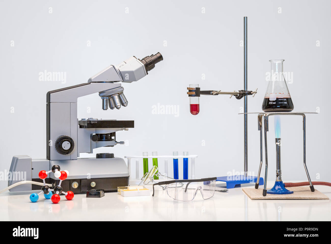 Science bench with microscope chemicals and a bunsen burner plus other equipment Stock Photo