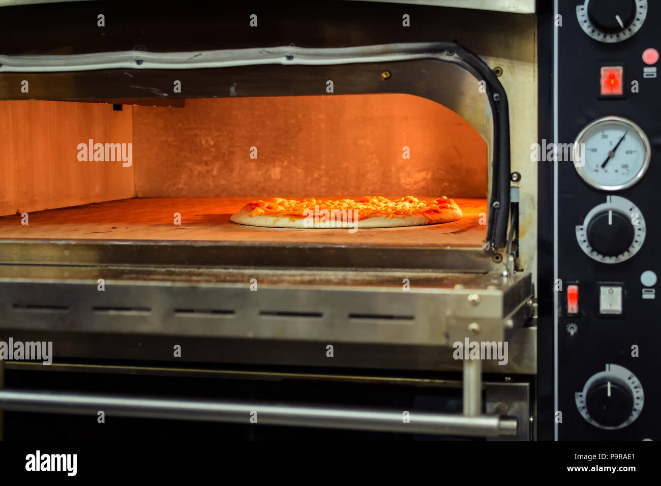 Cooking pizza in an electric oven in a restaurant, close up Stock Photo