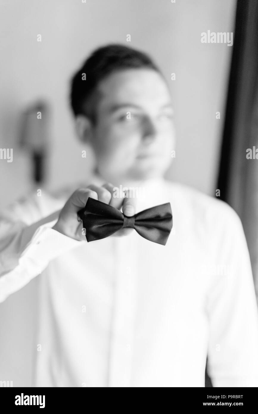 Close-up view of the bow-tie in the hand of the groom. Photo in black colours. Stock Photo