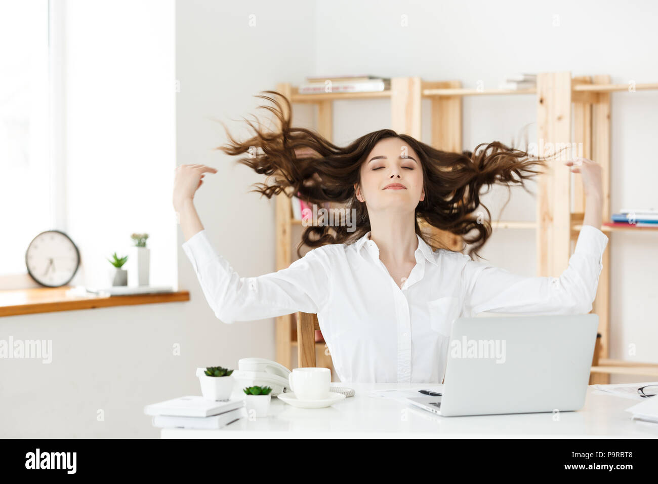 Portrait of smiling pretty young business woman sitting on workplace ...